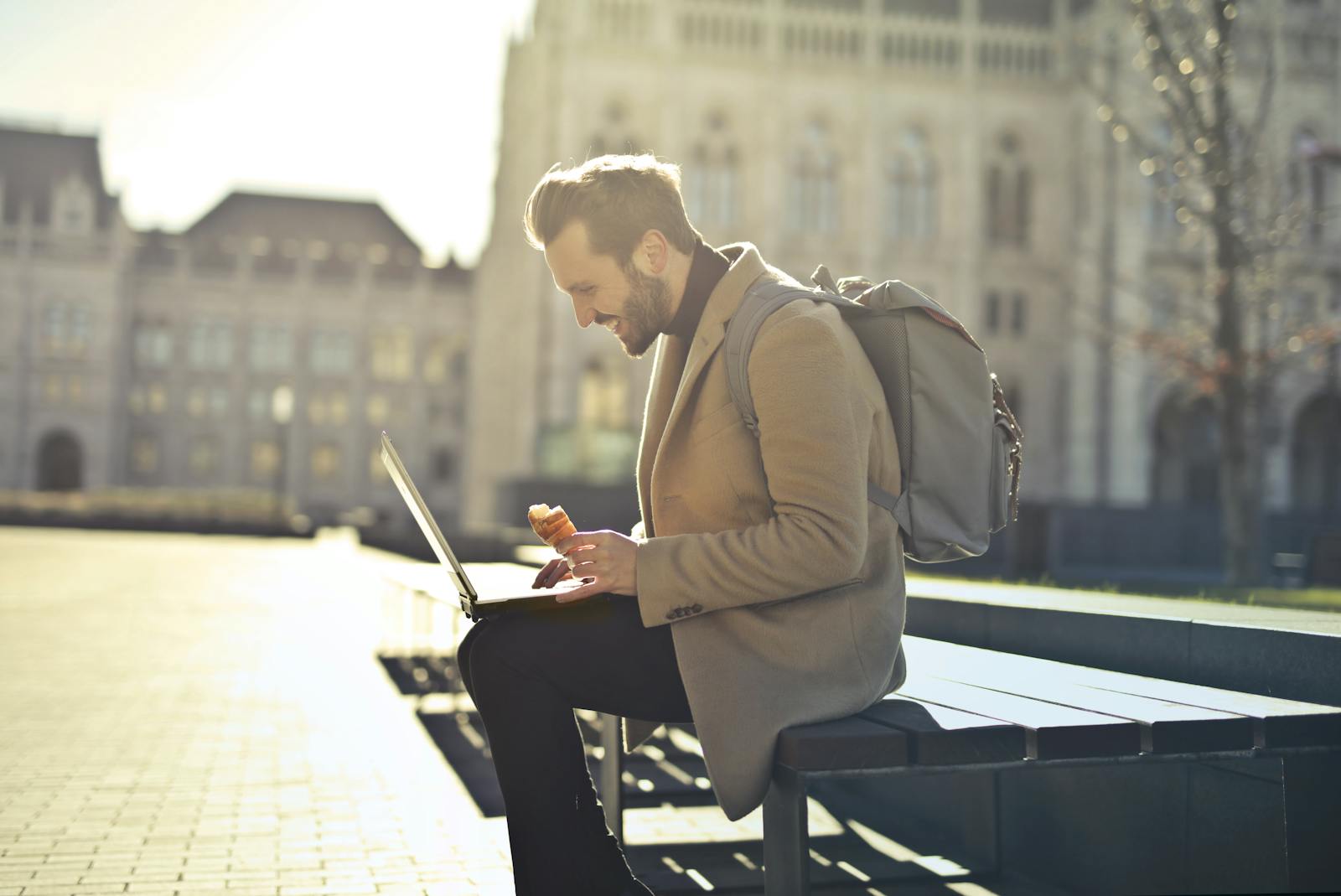 Man working on laptop in Budapest park while enjoying ice cream, showcasing remote work lifestyle.